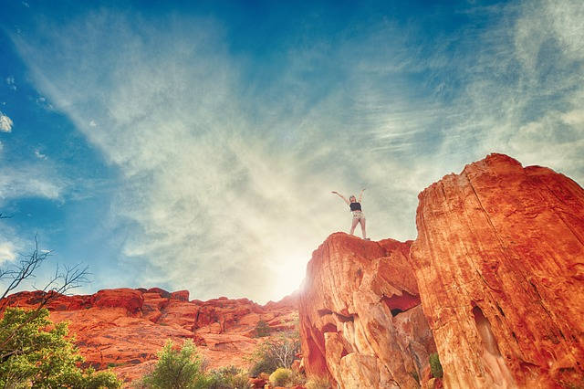 Femme heureuse sur un rocher rouge sous le ciel
